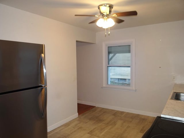 kitchen with stove, sink, ceiling fan, light wood-type flooring, and stainless steel refrigerator