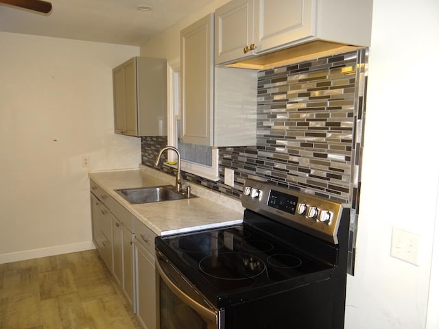 kitchen featuring decorative backsplash, light wood-type flooring, stainless steel electric stove, and sink