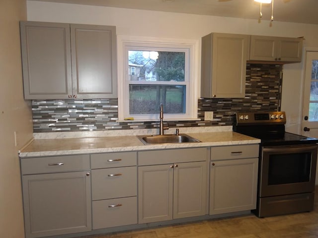 kitchen featuring decorative backsplash, electric range, gray cabinets, and sink