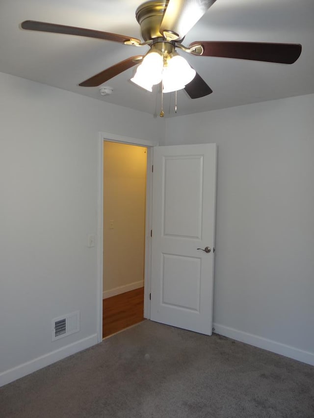 empty room with dark carpet and ceiling fan