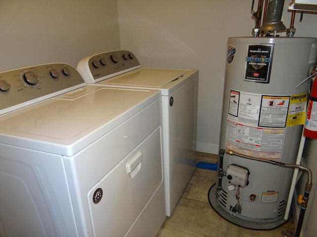 washroom with washing machine and dryer, light tile patterned floors, and gas water heater