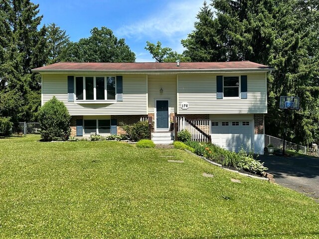 raised ranch with a garage and a front lawn