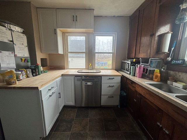 kitchen with stainless steel dishwasher, dark brown cabinetry, sink, white cabinets, and butcher block countertops