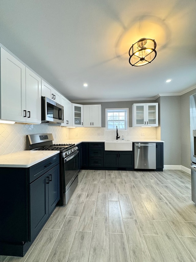 kitchen with sink, tasteful backsplash, crown molding, stainless steel appliances, and white cabinets