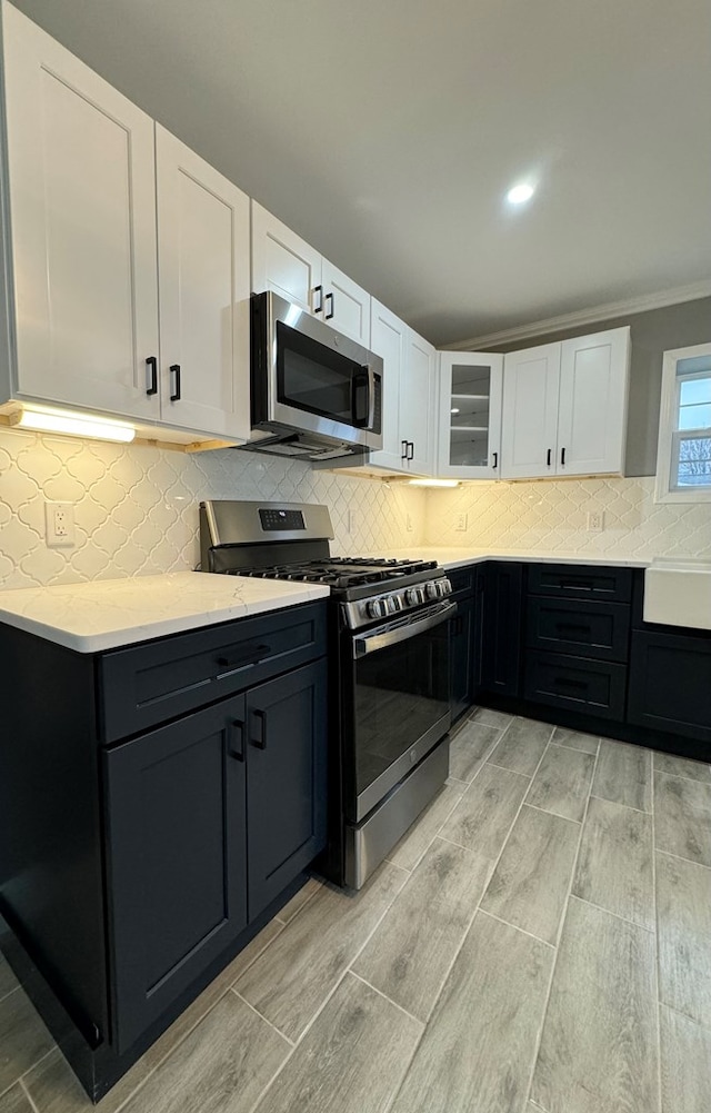 kitchen with tasteful backsplash, light stone counters, stainless steel appliances, and white cabinets