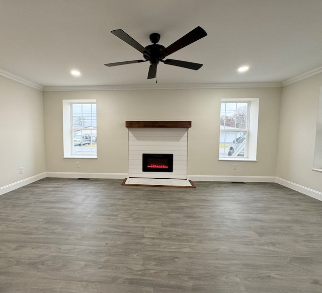 unfurnished living room featuring crown molding, a healthy amount of sunlight, ceiling fan, and dark hardwood / wood-style flooring