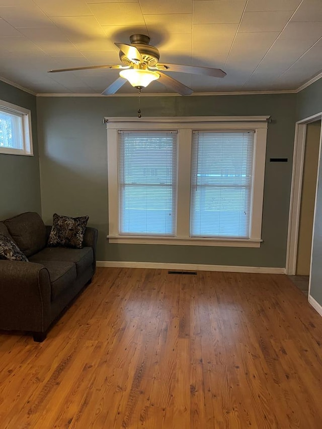 unfurnished living room with hardwood / wood-style floors, ceiling fan, and crown molding