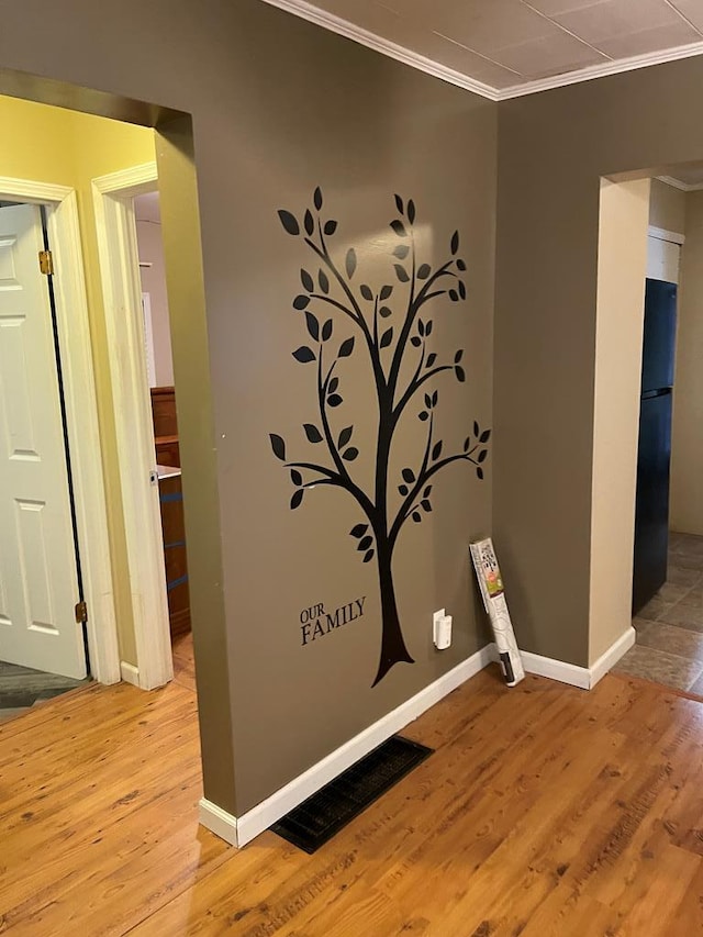 details featuring black fridge, wood-type flooring, and ornamental molding