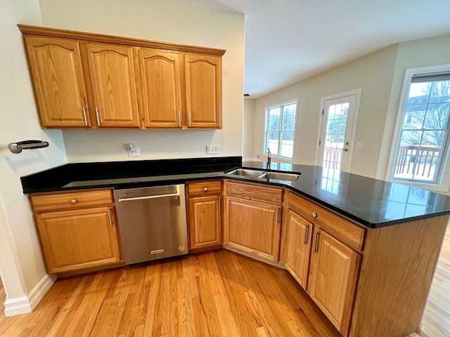 kitchen featuring sink, dishwasher, kitchen peninsula, dark stone counters, and light wood-type flooring