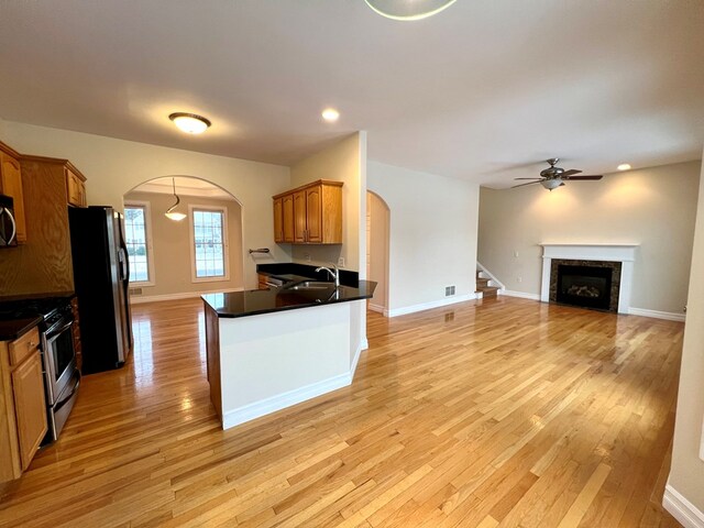 kitchen featuring sink, ceiling fan, appliances with stainless steel finishes, light hardwood / wood-style floors, and kitchen peninsula