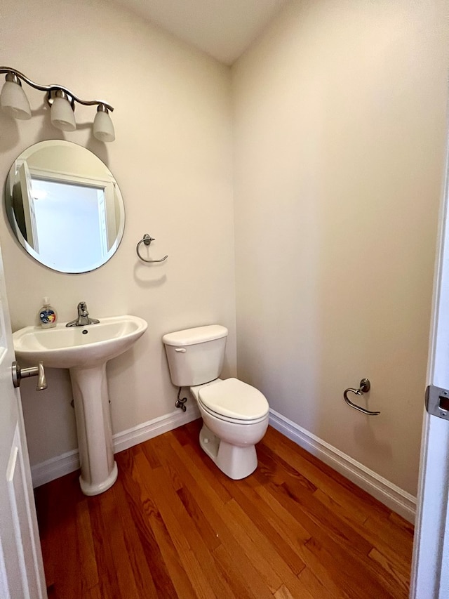 bathroom with hardwood / wood-style flooring, toilet, and sink