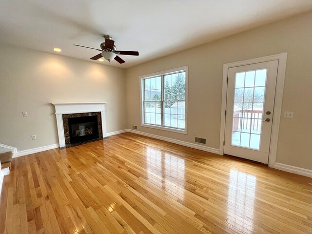 unfurnished living room with ceiling fan, a high end fireplace, and light hardwood / wood-style floors