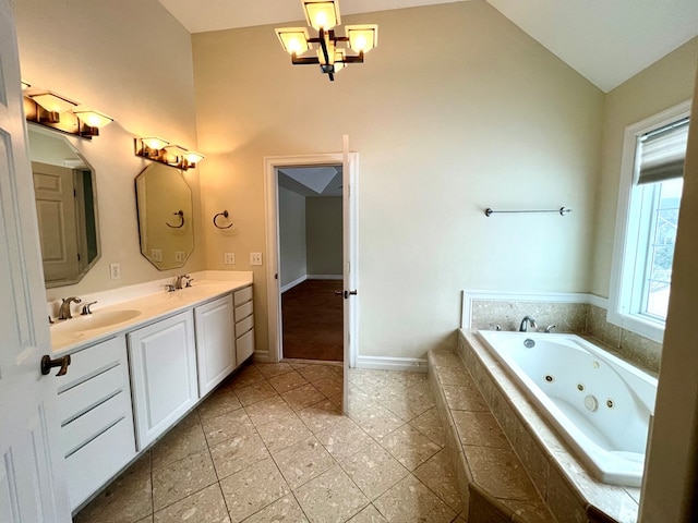 bathroom with an inviting chandelier, vanity, tiled bath, and vaulted ceiling