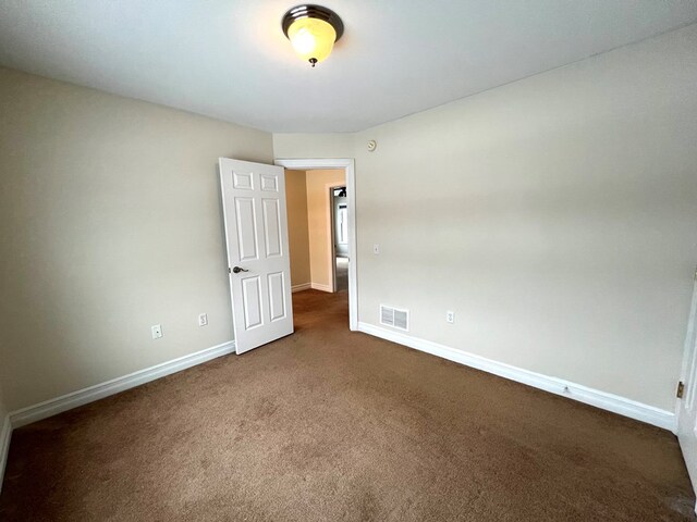 spare room with dark colored carpet