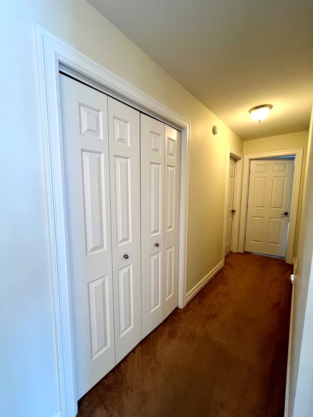 hallway featuring dark colored carpet