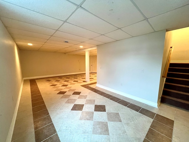 basement featuring a paneled ceiling and tile patterned flooring