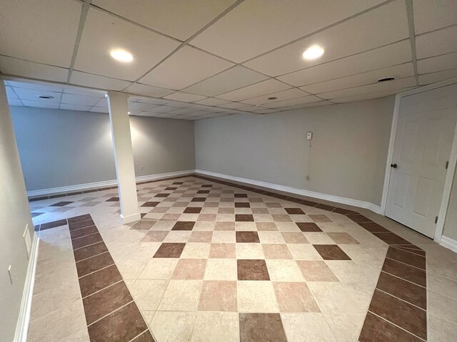 basement featuring a drop ceiling and light tile patterned flooring