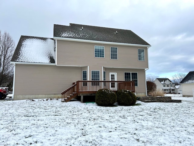 snow covered back of property with a wooden deck