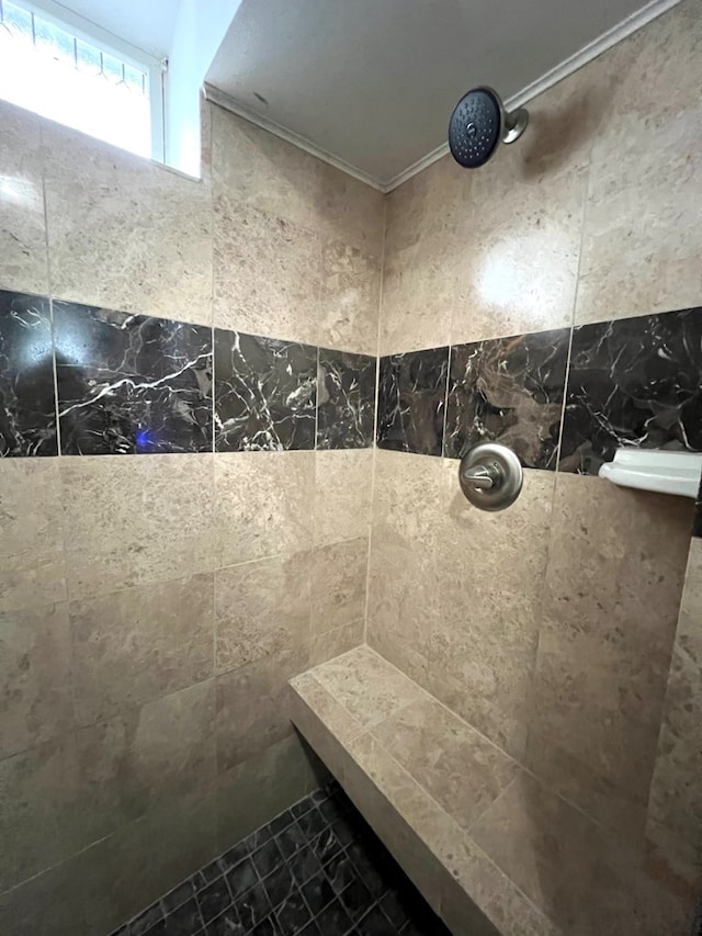 bathroom featuring ornamental molding and tiled shower