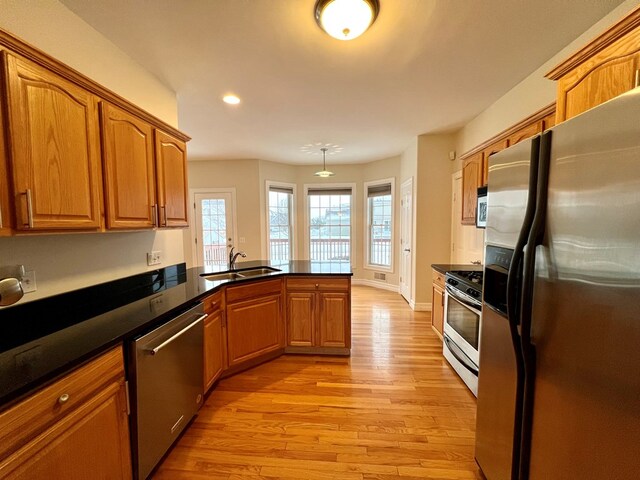 kitchen with sink, stainless steel appliances, kitchen peninsula, and light wood-type flooring