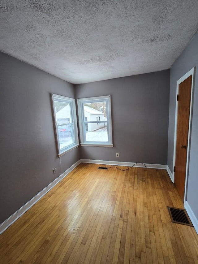 empty room with a textured ceiling and light wood-type flooring