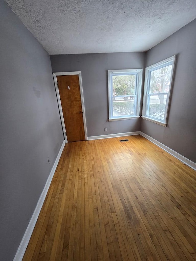 empty room with a textured ceiling and light wood-type flooring