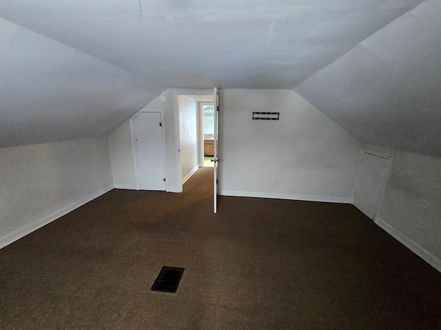 bonus room featuring dark carpet and vaulted ceiling