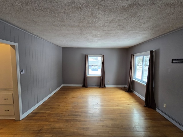 unfurnished room with a textured ceiling, light hardwood / wood-style floors, and wood walls