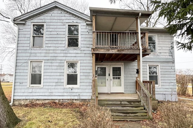 back of house with a balcony, a yard, and french doors