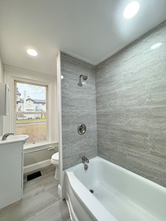 full bathroom with hardwood / wood-style flooring, vanity, toilet, and tiled shower / bath combo