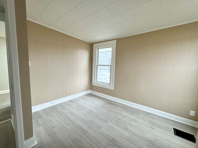 empty room with light wood-type flooring and wooden walls