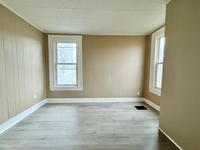 spare room with light hardwood / wood-style floors and wooden walls