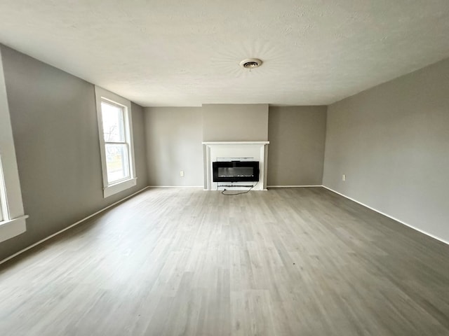 unfurnished living room featuring light hardwood / wood-style floors and a textured ceiling