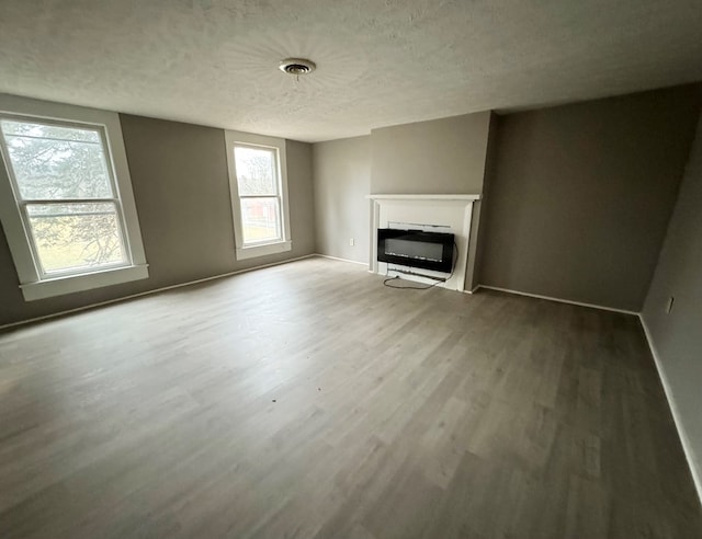 unfurnished living room featuring hardwood / wood-style floors, a fireplace, and a textured ceiling