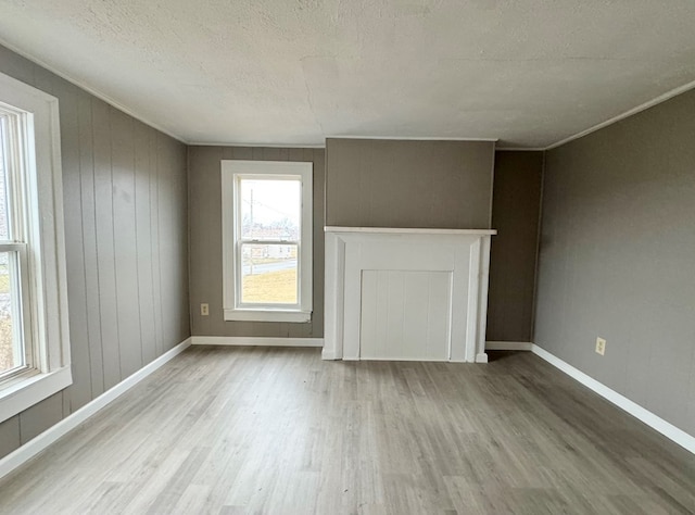 unfurnished living room featuring hardwood / wood-style floors, crown molding, and a textured ceiling