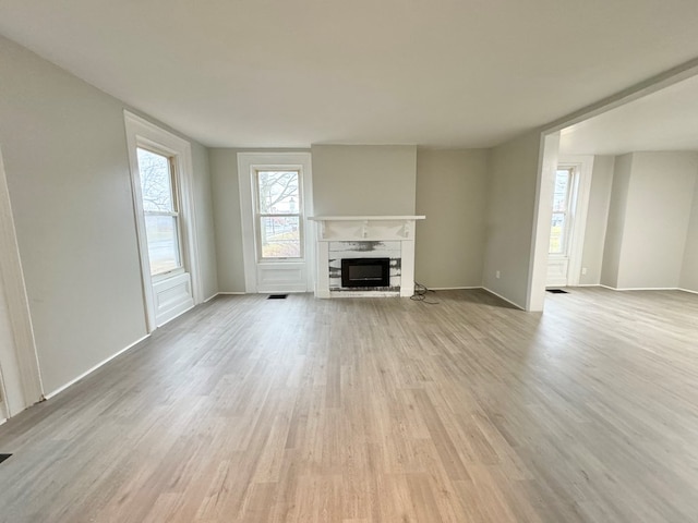 unfurnished living room featuring a fireplace and light hardwood / wood-style floors