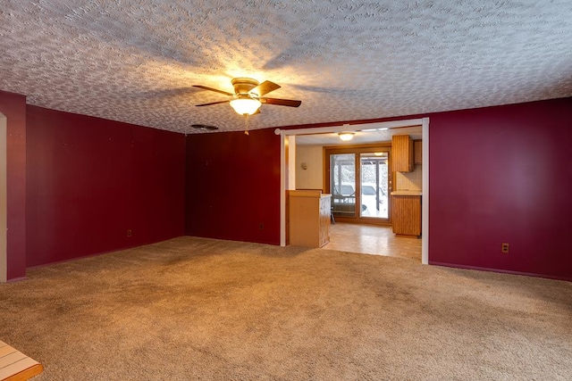 carpeted spare room with a textured ceiling and ceiling fan