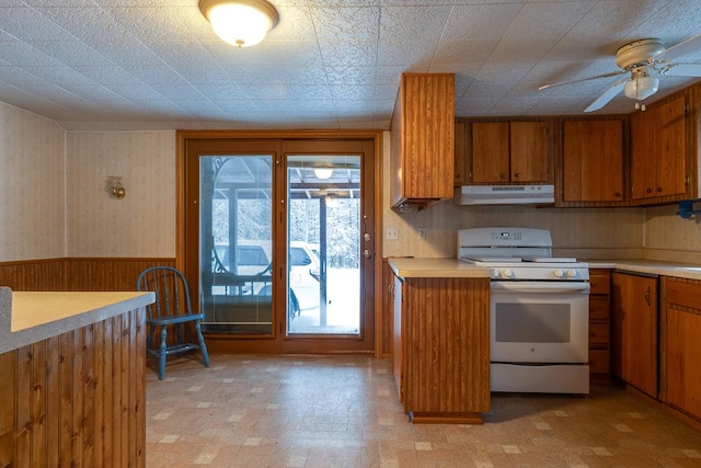 kitchen featuring ceiling fan, white range oven, and wooden walls