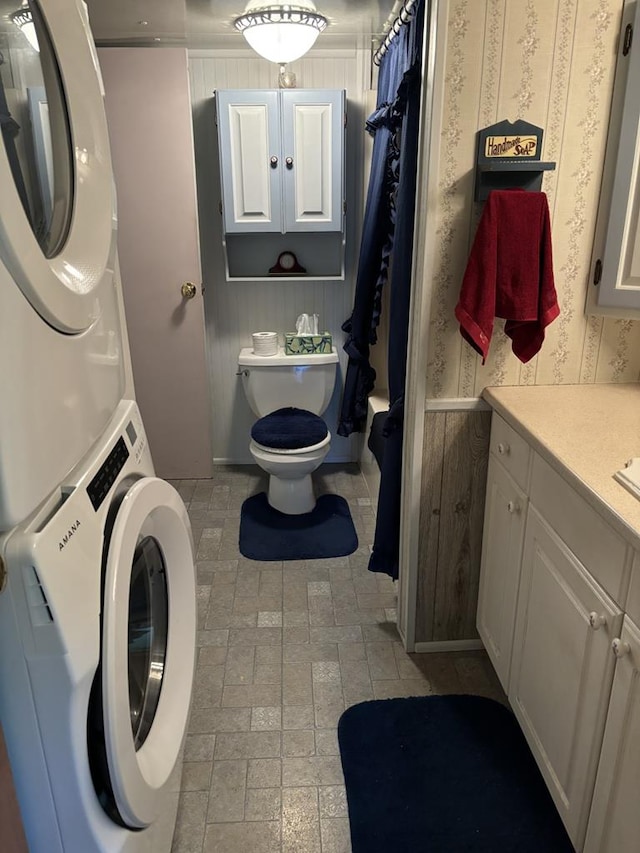 bathroom with stacked washer and dryer, vanity, and toilet