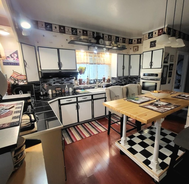 kitchen with a kitchen breakfast bar, stainless steel oven, and white cabinets