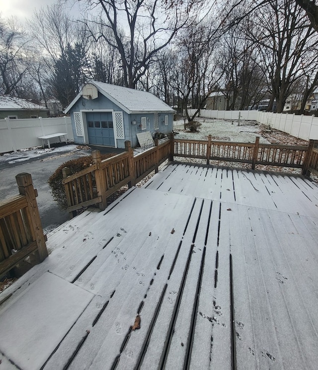 snow covered deck with a garage and an outdoor structure