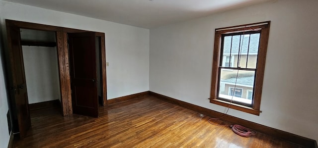 unfurnished bedroom with dark hardwood / wood-style flooring and a closet