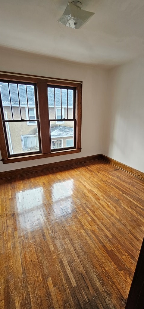 spare room with wood-type flooring and a healthy amount of sunlight