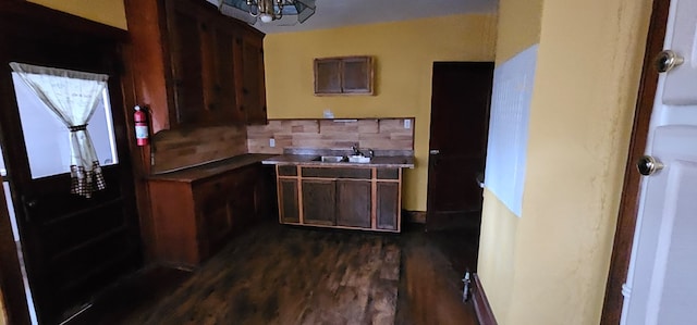 kitchen featuring sink, dark wood-type flooring, an inviting chandelier, dark brown cabinetry, and decorative backsplash