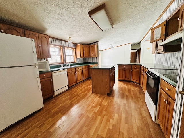 kitchen with a textured ceiling, white appliances, ceiling fan, hardwood / wood-style flooring, and a kitchen island