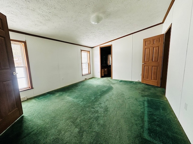 empty room featuring a textured ceiling, dark carpet, and plenty of natural light