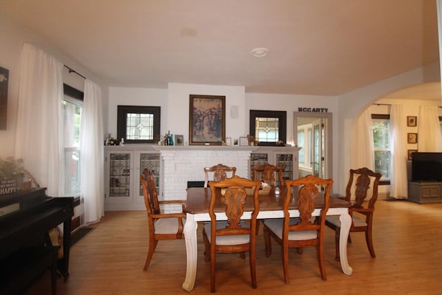 dining room featuring light wood-type flooring and a brick fireplace