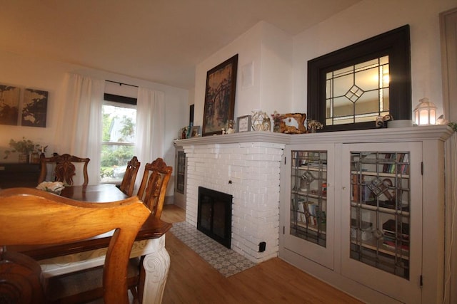 dining space featuring hardwood / wood-style floors and a brick fireplace