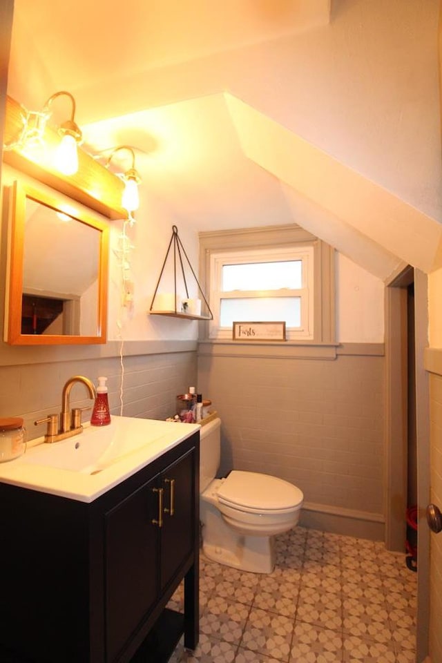 bathroom featuring vanity, toilet, and tile walls