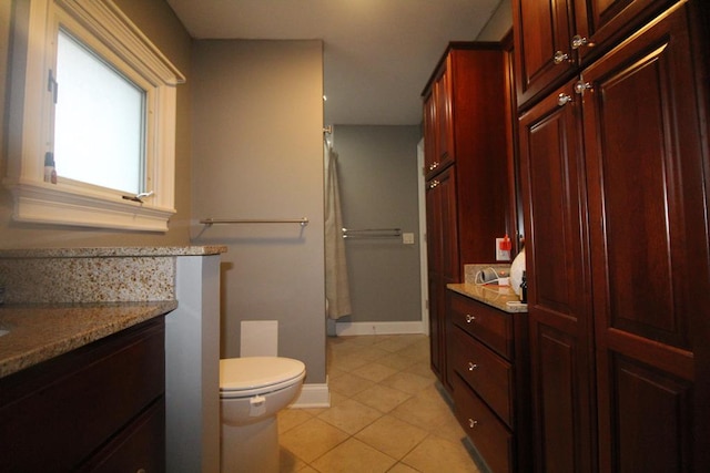 bathroom with toilet, vanity, and tile patterned floors